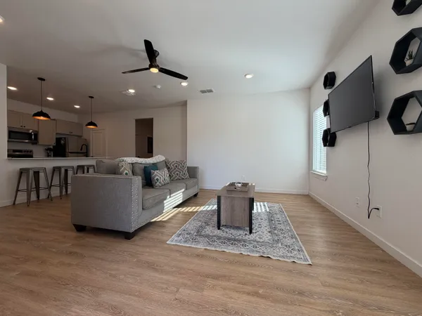 a living room with couches and kitchen view with wooden floor