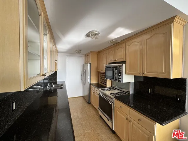 a kitchen with granite countertop stainless steel appliances a stove refrigerator and cabinets