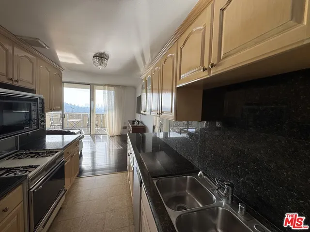 a kitchen with granite countertop stainless steel appliances a sink stove top oven and cabinets