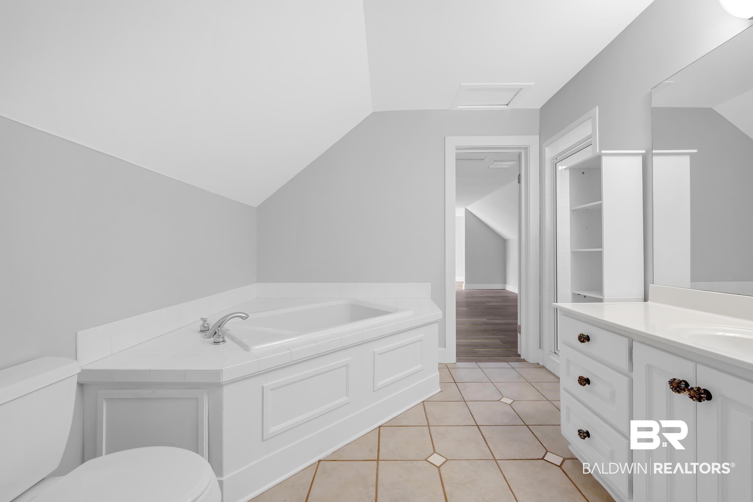 43199 Pine Grove Road Bay Minette, AL 36507 - Photo 62 of 71 Bright bathroom featuring a corner soaking tub with panel detailing, a double vanity with ample storage, a built-in shelving unit, and patterned tile flooring