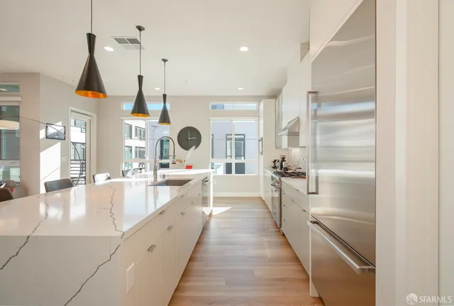 a large kitchen with stainless steel appliances kitchen island granite countertop a large counter top a stove and a chandelier