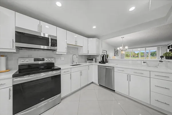 a kitchen with white cabinets appliances and a sink