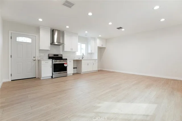 a view of a kitchen with a sink and dishwasher a stove top oven with wooden floor
