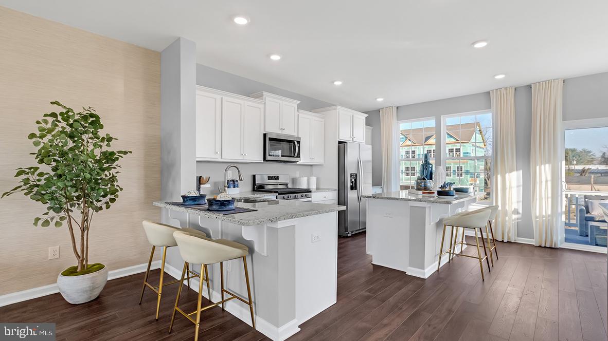 a kitchen with stainless steel appliances a white table a chair a window and cabinets