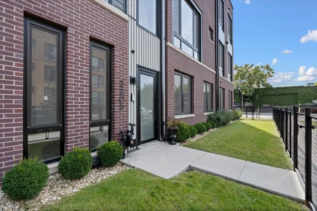 a view of a brick house with a yard and plants