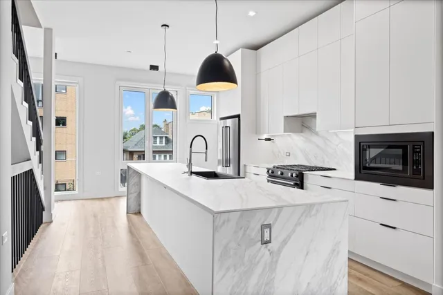 a kitchen with stainless steel appliances granite countertop a stove a sink dishwasher a refrigerator white cabinets and wooden floor