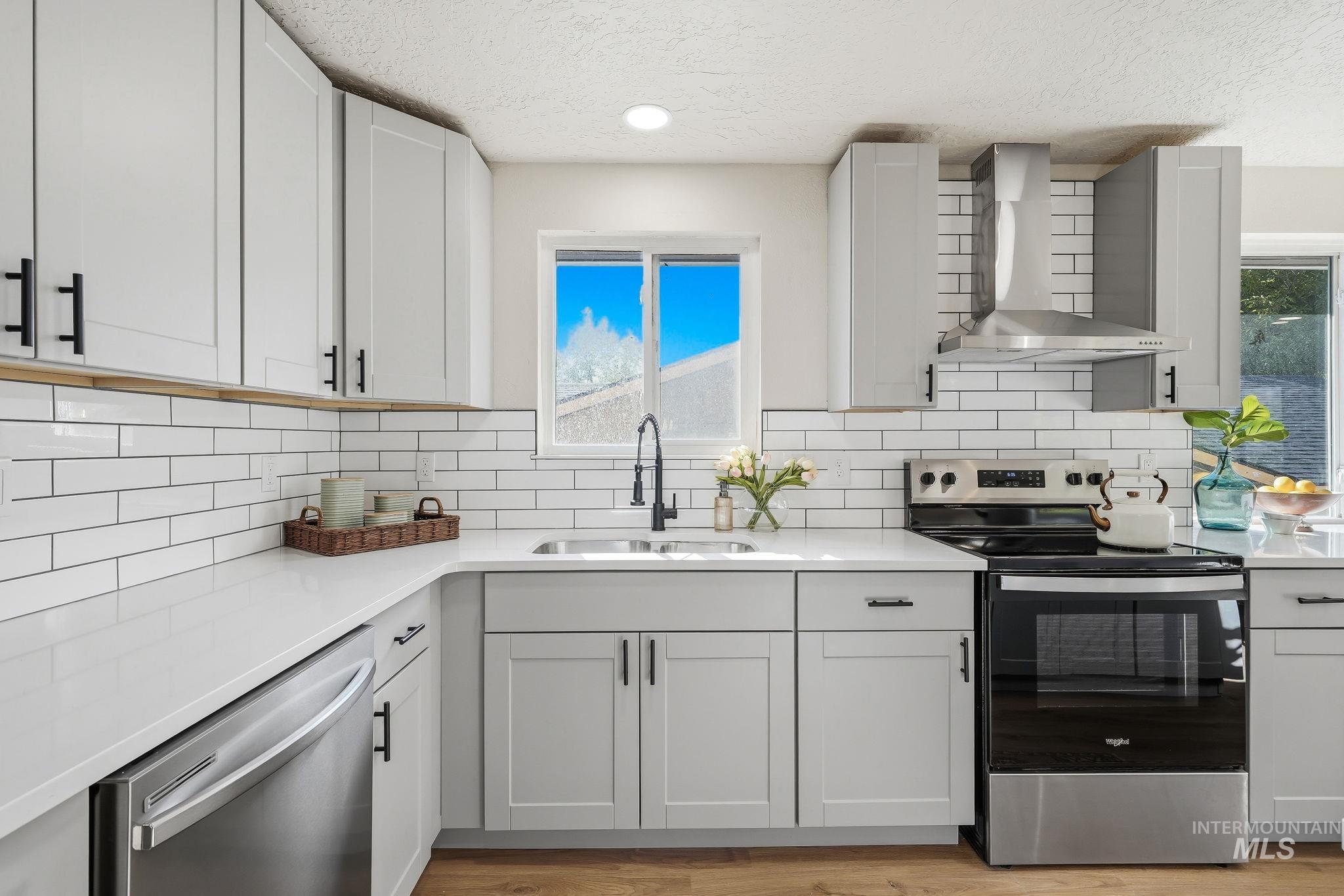 1990 Panama Street Boise, ID 83705 - Photo 27 of 50 Kitchen featuring light gray cabinetry, white subway tile backsplash, white countertops, stainless steel appliances, and wood-finish flooring