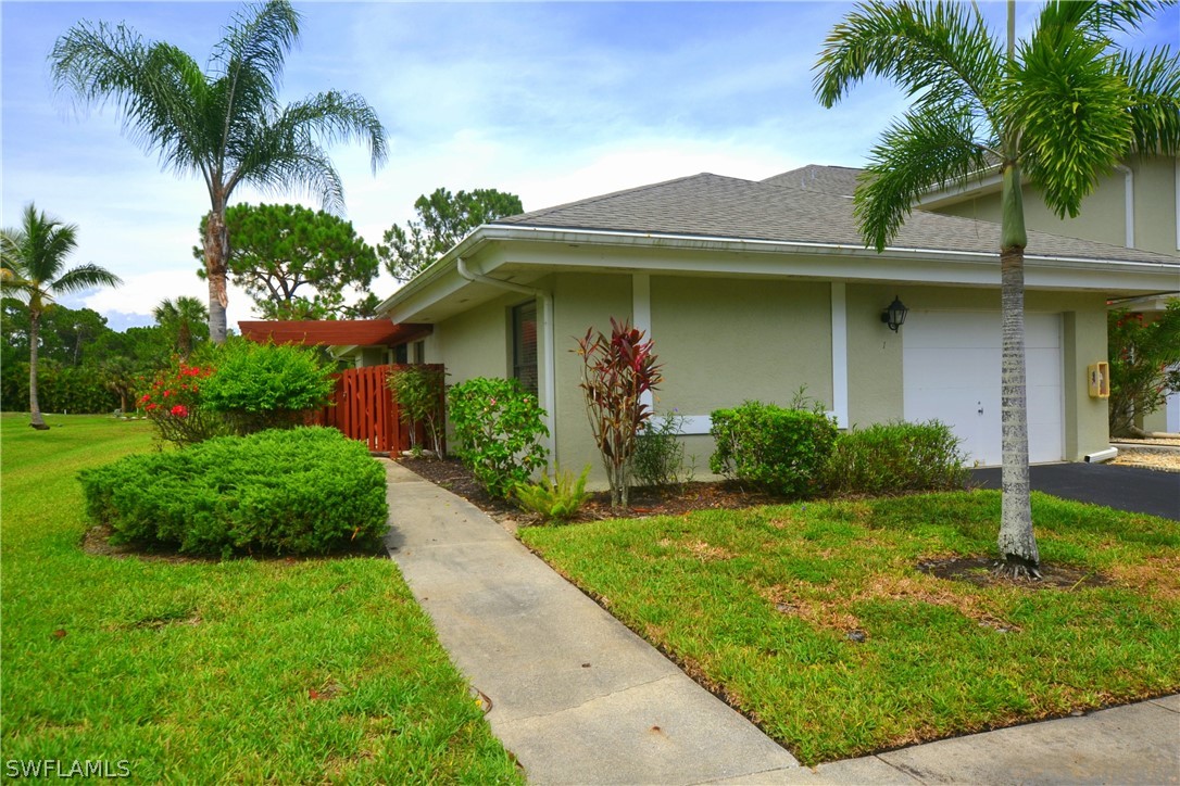 a front view of a house with a garden and palm trees