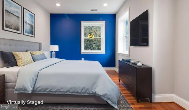 a bedroom with a bed and a flat tv screen on dresser