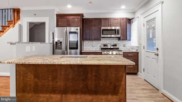 a kitchen with stainless steel appliances granite countertop a refrigerator a stove top oven a sink and dishwasher