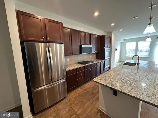 a kitchen with stainless steel appliances granite countertop a refrigerator a stove and a sink