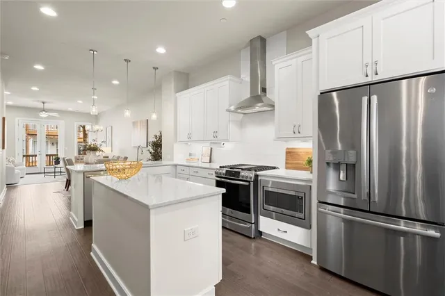 a kitchen with stainless steel appliances granite countertop a sink a stove a refrigerator and a oven with wooden floor