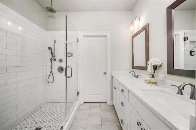 a spacious bathroom with a double vanity sink a mirror and shower