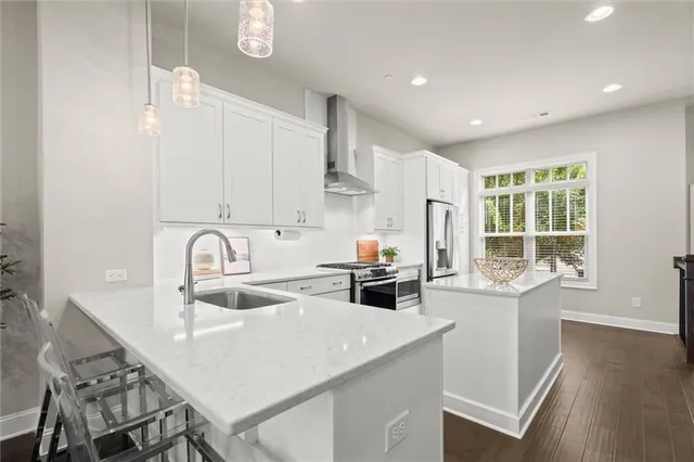 a kitchen with a sink a stove a refrigerator and white cabinets with wooden floor