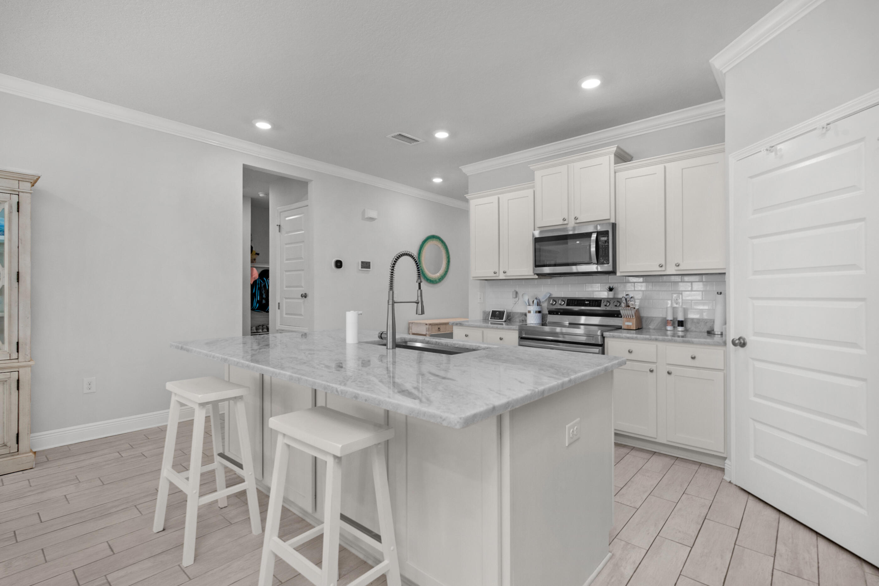 382 Lightning Bug Lane Freeport, FL 32439 - Photo 9 of 33 a kitchen with stainless steel appliances granite countertop a sink a stove a microwave a island with white cabinets and wooden floor