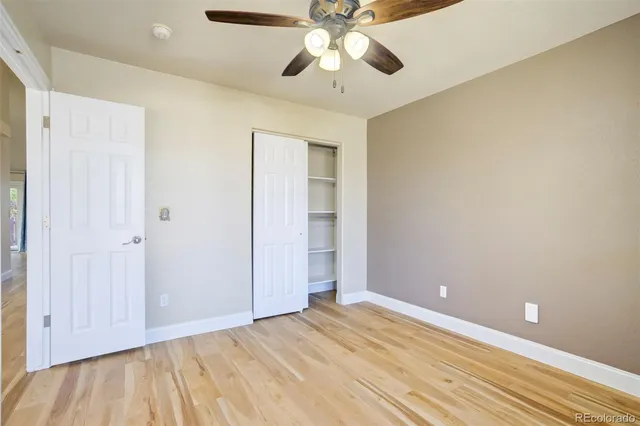 an empty room with a ceiling fan and wooden floor