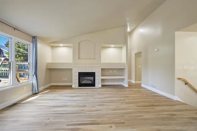 a view of empty room with wooden floor and fireplace