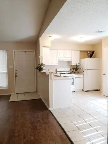 a kitchen with a sink a stove a refrigerator and white cabinets