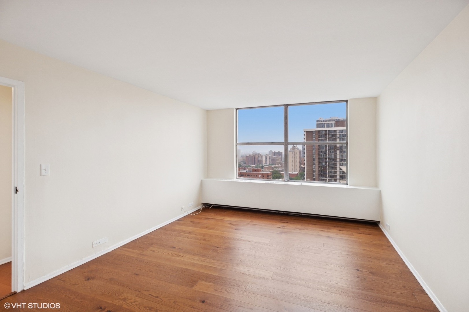 5757 North Sheridan Road, Unit 20J Chicago, IL 60660 - Photo 12 of 20 a view of an empty room with wooden floor and a window