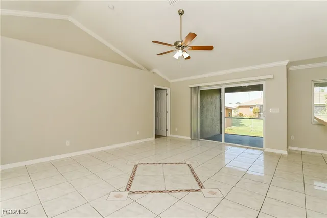 a view of an empty room and window with a chandelier fan