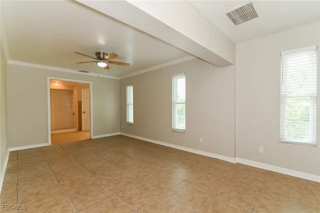 an empty room with windows and chandelier fan