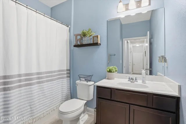 a bathroom with a sink a toilet and shower curtain