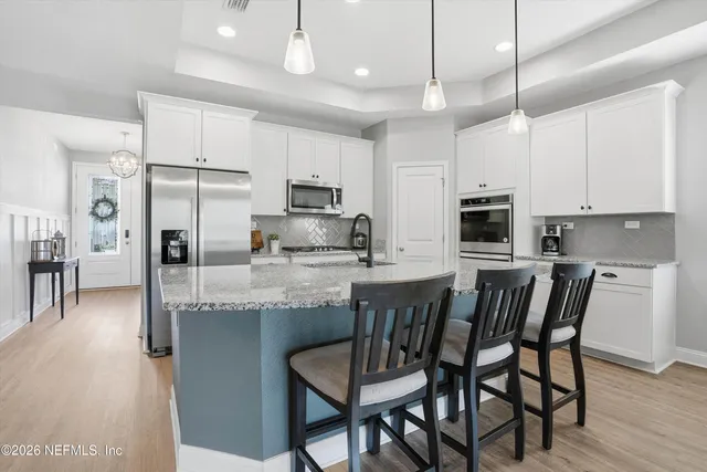 a kitchen with kitchen island granite countertop a table chairs microwave and refrigerator