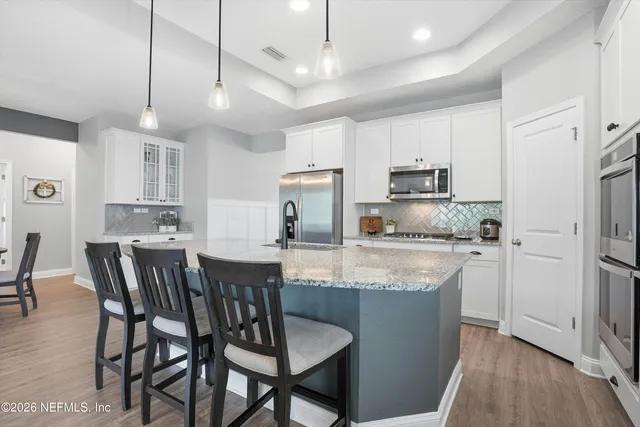 a kitchen with stainless steel appliances granite countertop a dining table chairs refrigerator sink and cabinets
