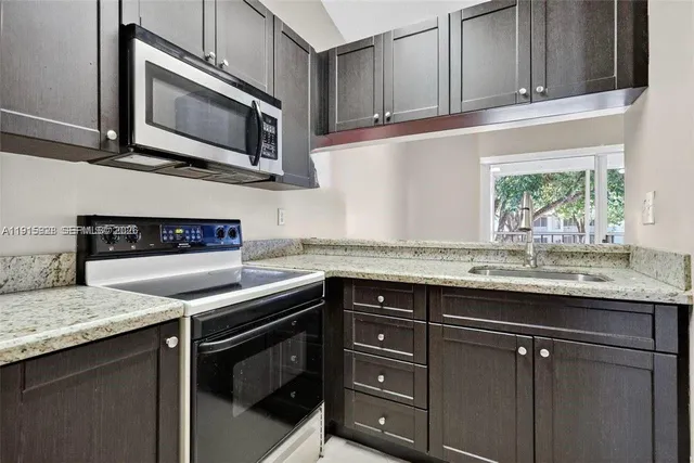 a kitchen with granite countertop a sink stainless steel appliances and cabinets