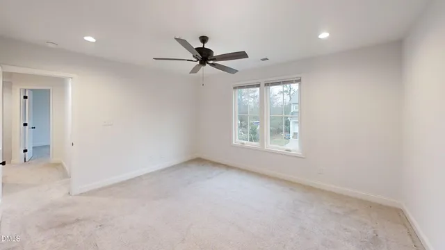 a view of empty room with window and ceiling fan