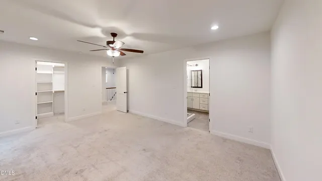 an empty room with chandelier fan and windows