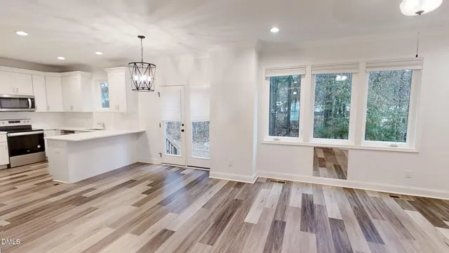 a large white kitchen with wooden floors and view living room