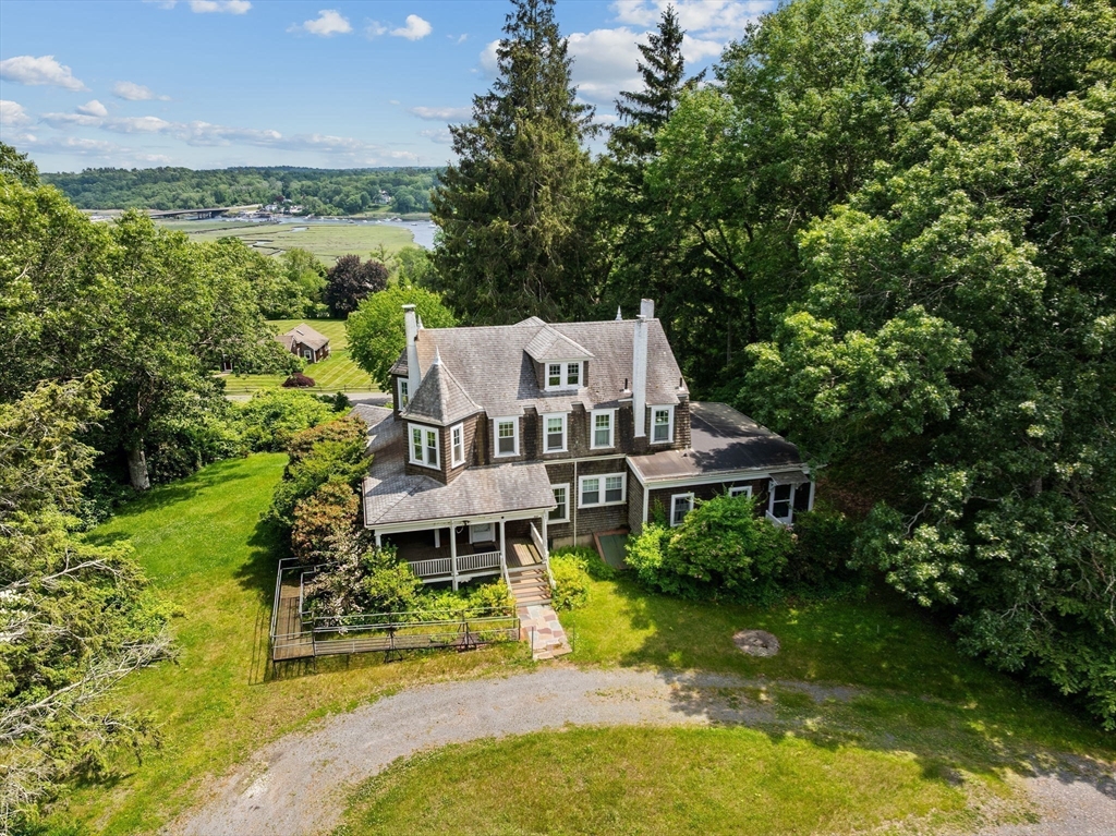 a aerial view of a house next to a big yard with plants and large trees