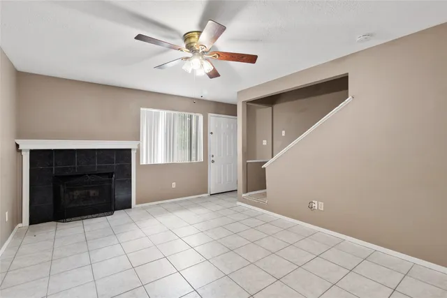 a view of an empty room with chandelier fan and fire place