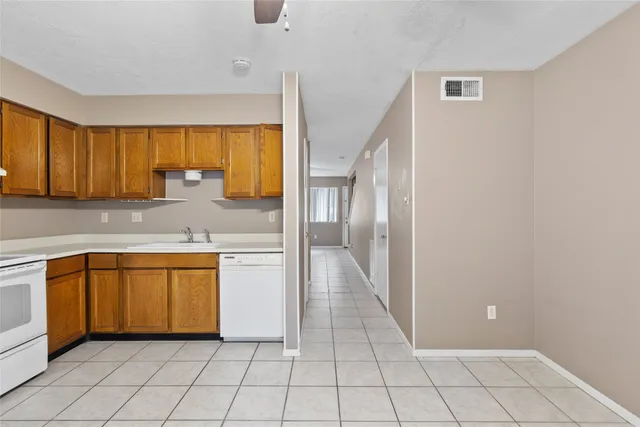 a large white kitchen with stainless steel appliances granite countertop a refrigerator and a sink