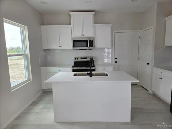 a white kitchen with sink and window