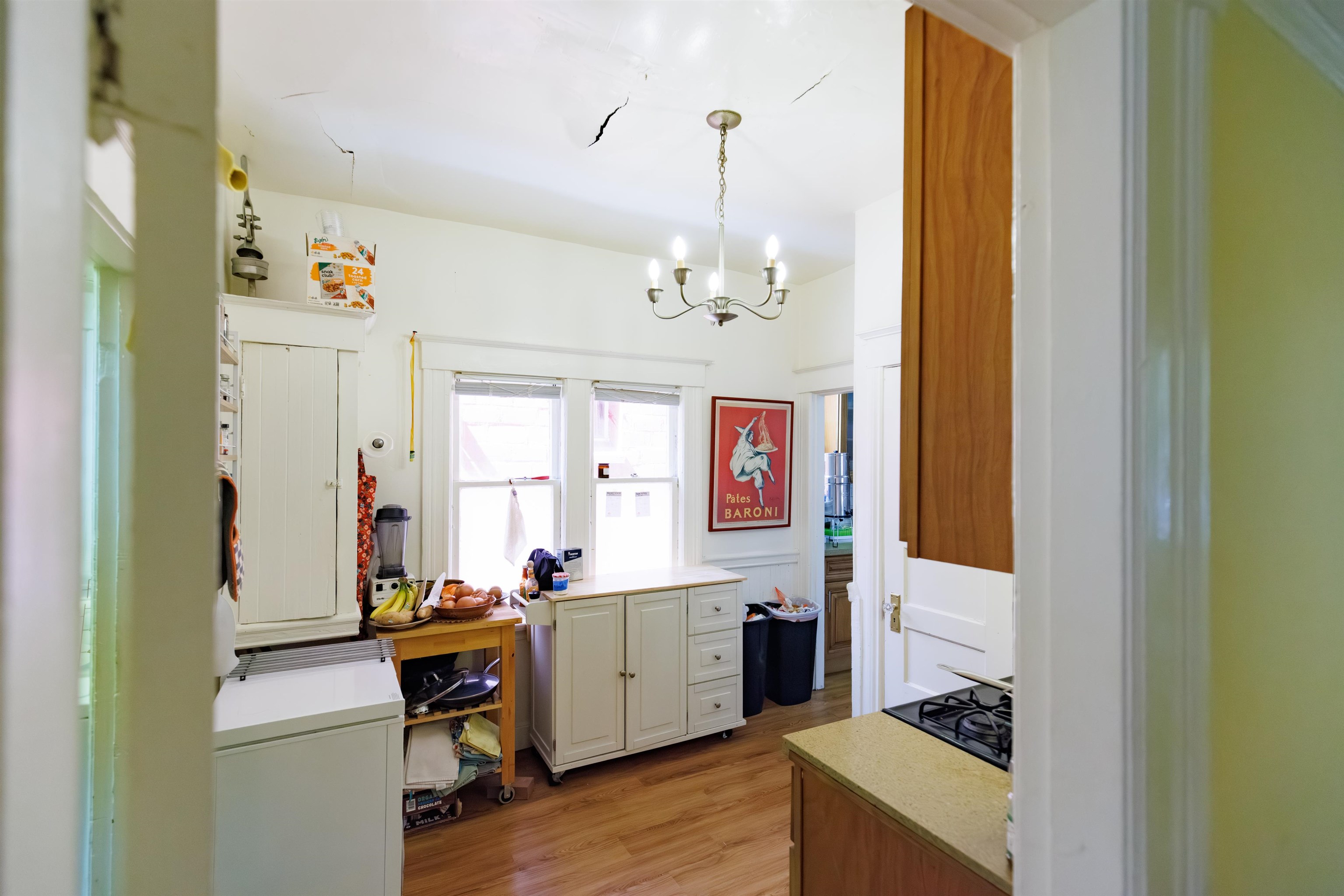 667 10th Street Oakland, CA 94607 - Photo 10 of 18 Kitchen featuring suspended lighting, light wood-style flooring, black gas cooktop, and white cabinets