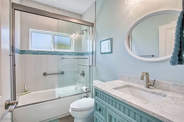 a bathroom with a granite countertop sink toilet mirror vanity and shower