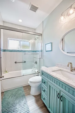 a bathroom with a granite countertop toilet a sink and a mirror