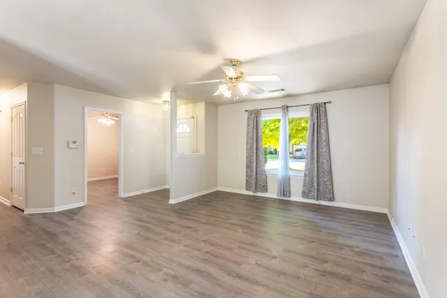 a view of an empty room with window and wooden floor