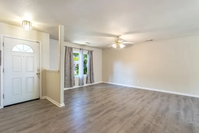 an empty room with wooden floor fan and window