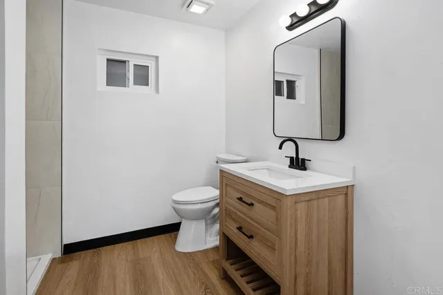 a view of a hallway with wooden floor and a bathroom