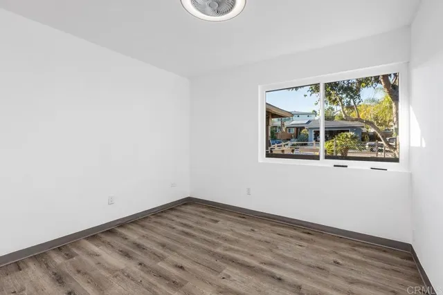 a living room with kitchen island granite countertop wooden floor and a ceiling fan