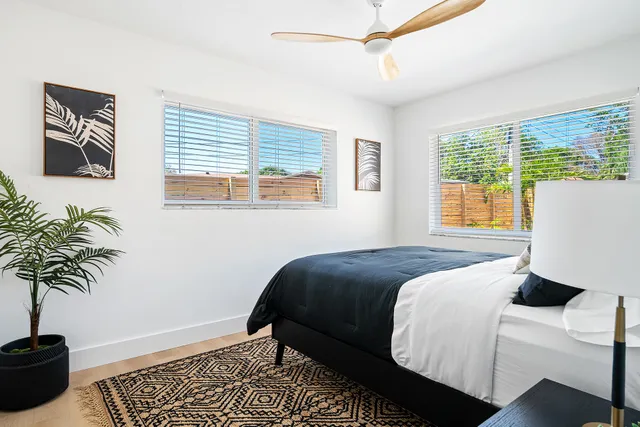 a bedroom with a bed and a window with potted plants