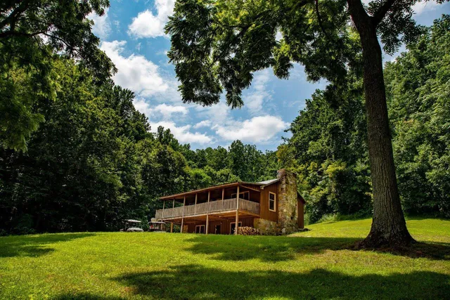a view of a house with a big yard and large trees