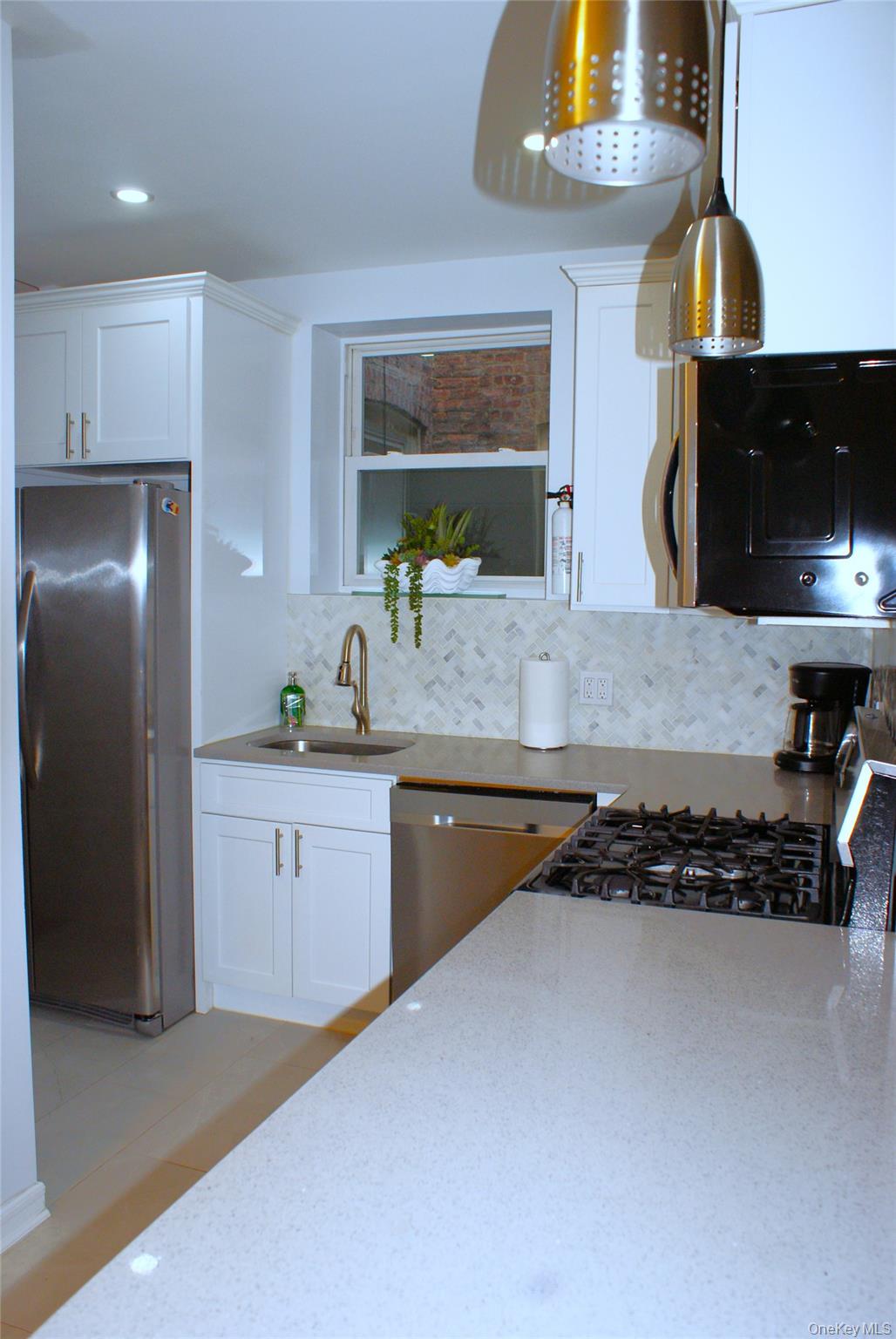 600 Flatbush Avenue Brooklyn, NY 11225 - Photo 7 of 17 Kitchen featuring stainless steel appliances, backsplash, white cabinetry, light stone countertops, and recessed lighting