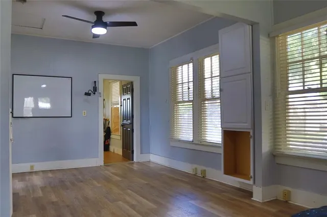 a view of an empty room with a window and wooden floor