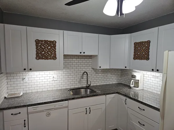 a kitchen with stainless steel appliances granite countertop a sink a stove and cabinets