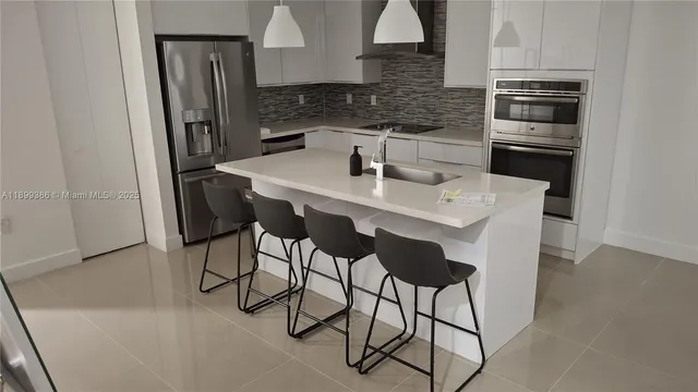 a kitchen with stainless steel appliances a dining table chairs and a refrigerator