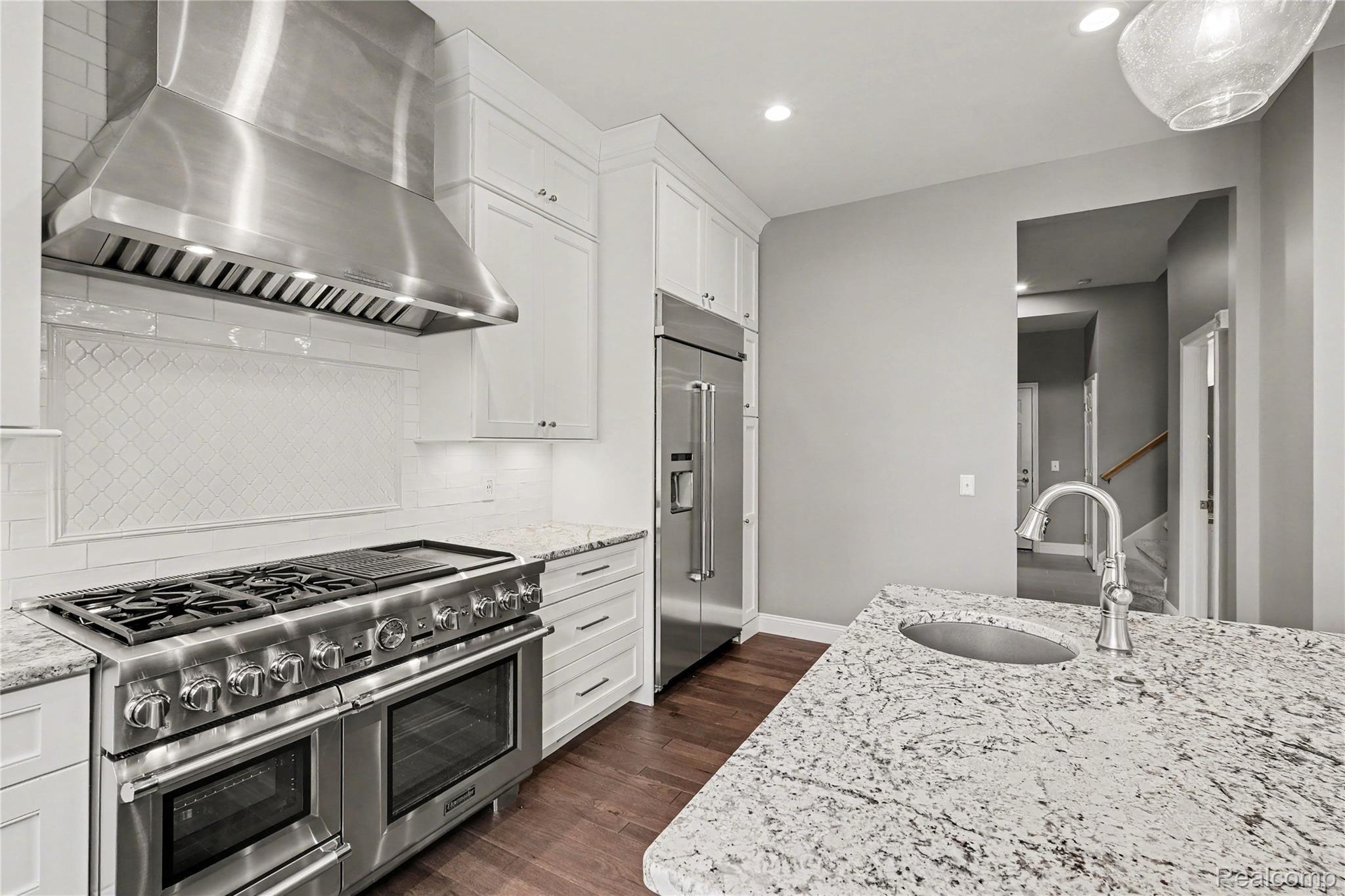 4179 St Andrews Street Howell, MI 48843 - Photo 15 of 75 Kitchen featuring high quality appliances, white cabinetry, light stone countertops, dark wood-style flooring, and recessed lighting